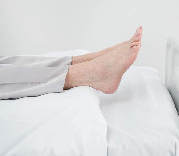 Side view of feet supported on Repose Flex, with bed sheet covering the Flex .  Feet and heels floating above the mattress.